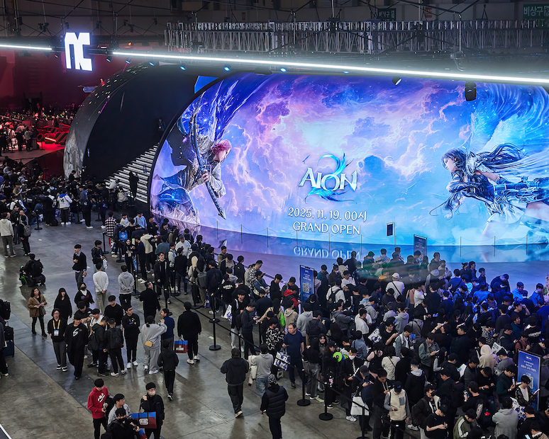 A massive Dome LED screen at the NCSOFT booth during G-STAR 2025 displays AION 2 promotional artwork and launch date, surrounded by large crowds of visitors lining up for game demos inside the exhibition hall.